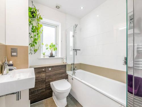 a bathroom with a toilet and a sink and a tub at Pass the Keys The Southside - Stylish Apartment with Private Terraces near Barnes & Putney in London