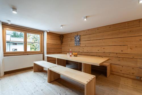a room with a wooden wall with a table and benches at Berghof Ferienhaus in Schröcken