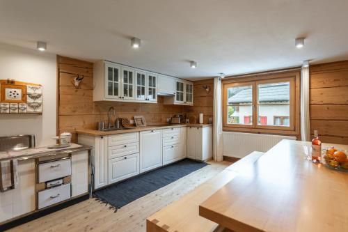 a kitchen with white cabinets and a wooden table at Berghof Ferienhaus in Schröcken
