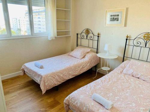 1 dormitorio con 2 camas, mesa y ventanas en Playa La Cortadura & Parking FREE Grupo AC Gestion, en Cádiz