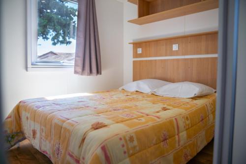 - une chambre avec un lit doté d'une tête de lit en bois et d'une fenêtre dans l'établissement Camping Parc Bellevue, à Cannes