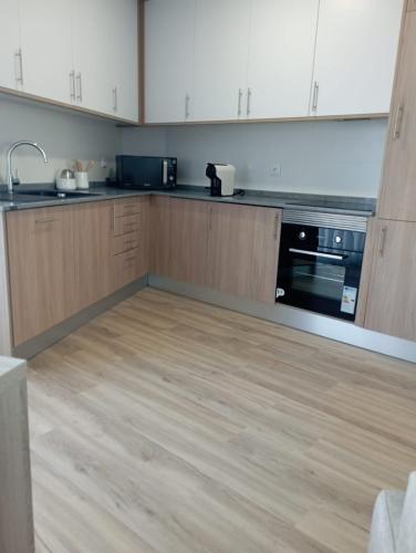 a kitchen with wooden cabinets and a wooden floor at Home Away in Vila Nova de Milfontes