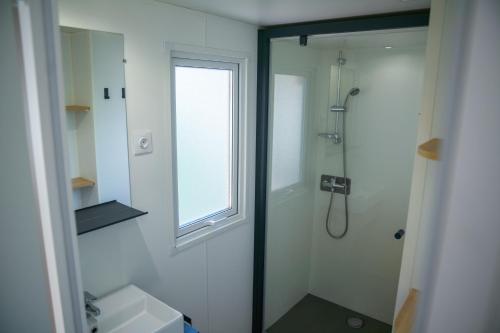 łazienka z prysznicem, umywalką i oknem w obiekcie Camping Parc Bellevue w Cannes