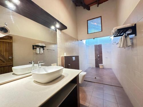 a white bathroom with a sink and a toilet at Kadkani River Resort in Siddapur