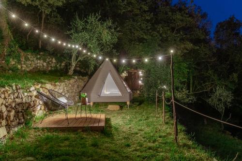 Chiusanico的住宿－Tipì - Glamping Experience，院子里的帐篷和椅子,配有灯