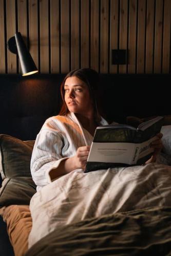 a woman laying in bed with a laptop at Ådalsvollen Retreat -Go Wild for a While, Private Nature Getaway in Verdal