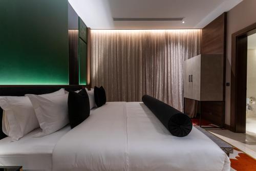 a bedroom with a large white bed with black pillows at Lilac Park Hotel in Tabuk