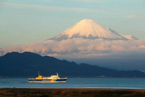 ein Kreuzfahrtschiff im Wasser vor einem Berg in der Unterkunft 韶光民泊 in Shizuoka