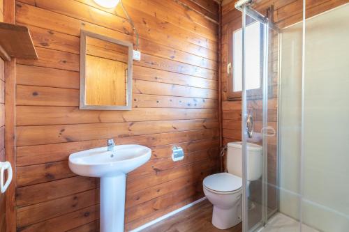 La salle de bains est pourvue de murs en bois, de toilettes et d'un lavabo. dans l'établissement Cabaña Madera A, à Bárig