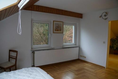 a bedroom with two windows and a bed and a chair at Wohnen im Wald in Alte Drusel