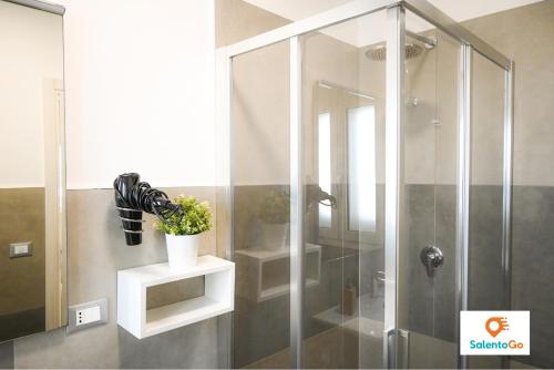 un bagno con doccia e pianta su una mensola di Stanze VILLA DEL CONTE a Punta Prosciutto by SalentoGo a Punta Prosciutto