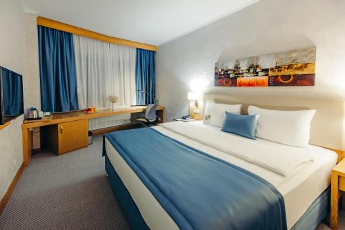 a hotel room with a large bed and a desk at Dedeman Oskemen Tavros Hotel in Ustʼ-Kamenogorsk