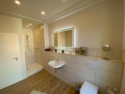 een badkamer met een wastafel, een toilet en een spiegel bij Ferienwohnung PIER 4 in Cuxhaven in Cuxhaven