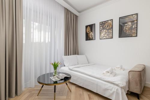 a white bedroom with a bed and a table at Hanza Tower Studio 317 in Szczecin