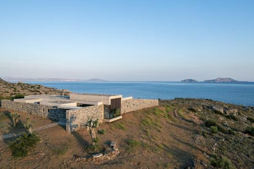 a building on top of a hill next to the ocean at Orizontes Villa, Tranquil SeaView Living, By ThinkVilla in Agios Pavlos