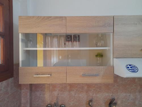 un armario de madera con puertas de cristal en la cocina en Paradise Studios, en Liapades
