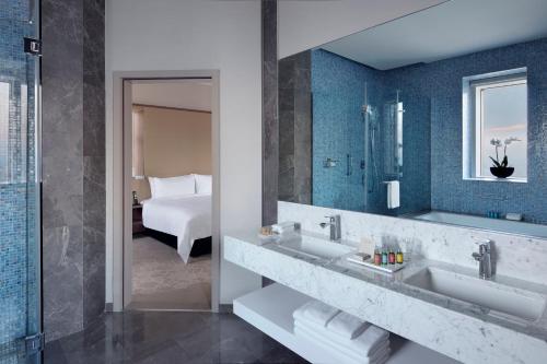 a bathroom with a sink and a mirror and a bed at Istanbul Marriott Hotel Sisli in Istanbul
