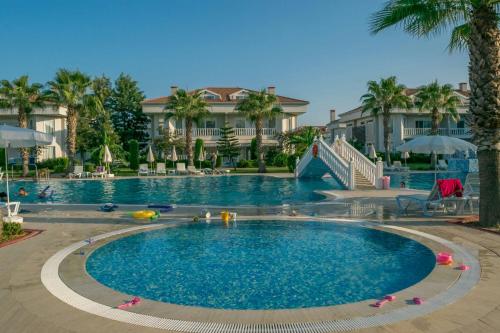 uma grande piscina num resort com palmeiras em BlueHomes Villas em Belek