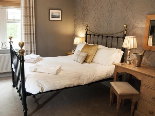 um quarto com uma cama grande com lençóis brancos e almofadas em The Poplars Rooms & Cottages em Thirsk