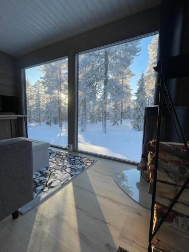 Cette chambre dispose d'une grande fenêtre offrant une vue sur les arbres enneigés. dans l'établissement WALD Villas - Aavasaksa, Lapland, à Aavasaksa