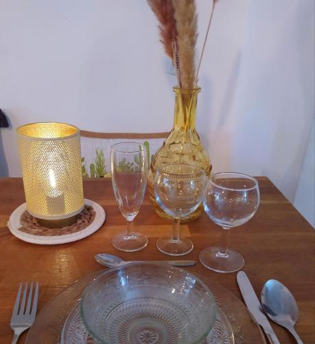 une table en bois avec trois verres à vin et un vase dans l'établissement Gîte de groupe Loire 42 salle de réception La Bâtisse aux Lanternes 30 couchages de charme spacieux classé 4 etoiles, à Saint-Bonnet-le-Château