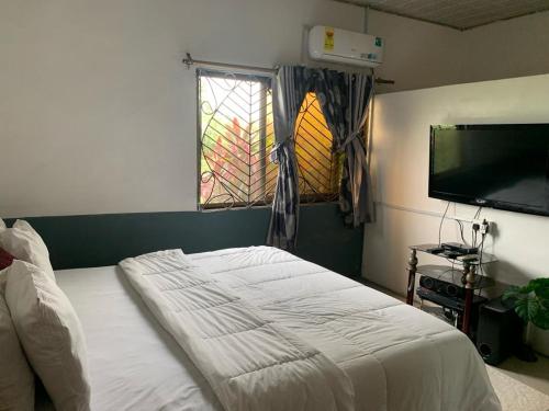 a bedroom with a bed and a flat screen tv at HOMELY GUEST HOUSE in Agona