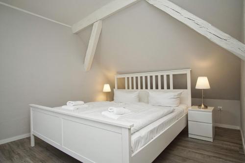 a white bed with two towels on it in a room at nah am Meer, ruhige Lage, gratis Nutzung vom AHOI Erlebnisbad und Sauna in Sellin - Haus Büdnerstube FeWo 4 in Middelhagen