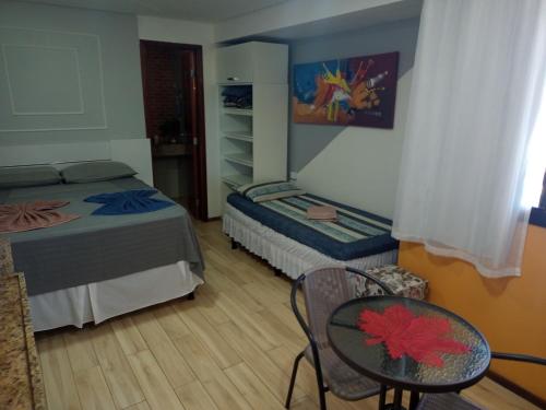a bedroom with a bed and a table and a chair at Flat pé na areia Tambaú in João Pessoa