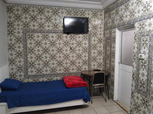 a bedroom with a bed and a table and a tv at Hotel Marhaba - Beb Bhar Tunis in Tunis
