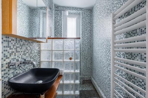 La salle de bains est pourvue d'un lavabo noir et d'une fenêtre. dans l'établissement Veeve - Honeybee Soul, à Paris