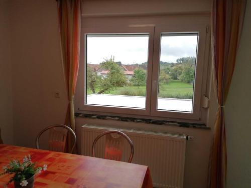 een eettafel met een tafel en twee ramen bij Ferienwohnung Renner ca 100 qm in Mühlingen