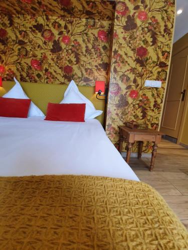 a bedroom with a large white bed with red pillows at Hotel de la Gaichel in Eischen