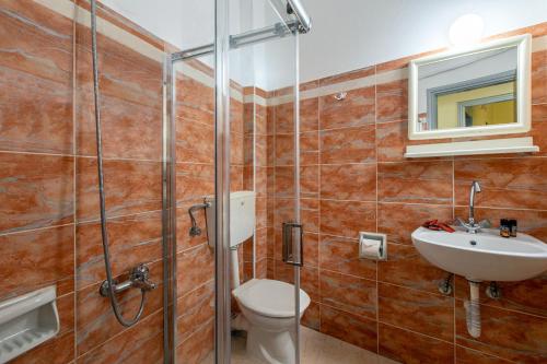 a bathroom with a shower and a toilet and a sink at Lucia Hotel in Chania