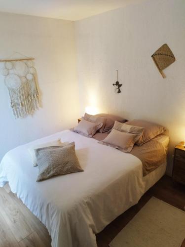 une chambre avec un grand lit blanc avec des oreillers dans l'établissement Charmant T2 terrasse, bord de mer, à Argelès-sur-Mer