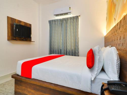 海得拉巴的住宿－Super OYO Flagship Big Daddy Suites，一间卧室配有一张带红色枕头的床和电视。