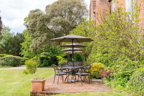 a table and chairs under an umbrella in a garden at Hintlesham Hall Hotel in Ipswich