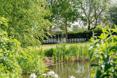 a gazebo in a park next to a pond at Hintlesham Hall Hotel in Ipswich
