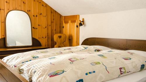 a bedroom with a bed with a comforter and a mirror at Hotel Chasseral in Nods