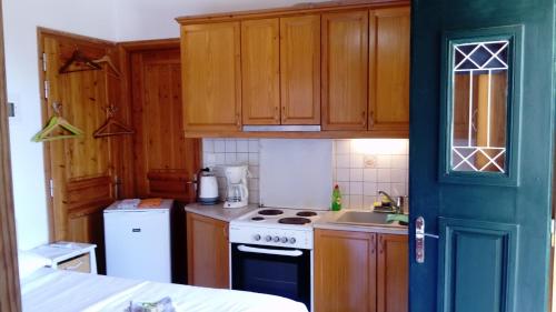 a kitchen with wooden cabinets and a stove top oven at zacharoularooms3 in Manganítis