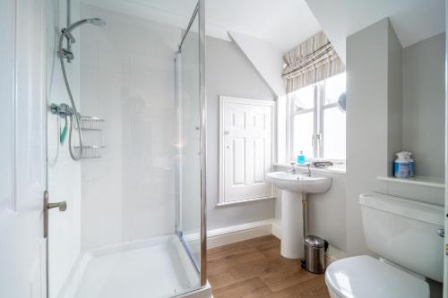 a white bathroom with a shower and a sink at Mahonia Cottage in Burnham Market
