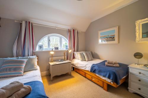 a bedroom with two beds and a window at Mahonia Cottage in Burnham Market