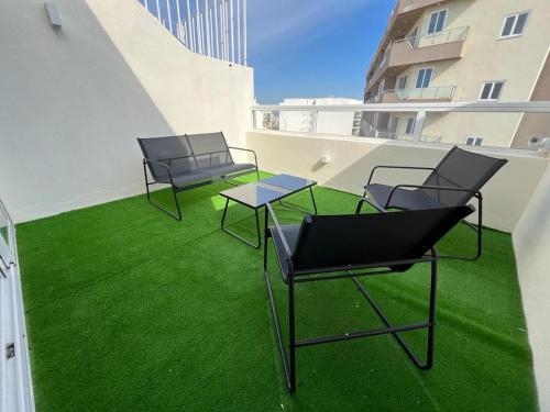 2 sillas y una mesa en un balcón con césped verde en Penthouse St Paul's Bay, en St Paul's Bay