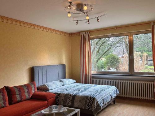 ein Schlafzimmer mit einem Bett, einem Sofa und einem Fenster in der Unterkunft Villa Engelskirchen in Engelskirchen