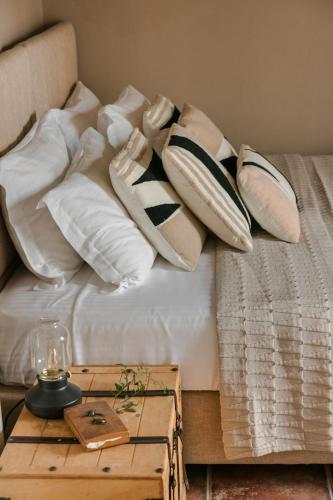 a bed with pillows on it with a wooden table at Scorpios Mansion Loft / Downtown Skala / Seaside in Skala Kefalonias