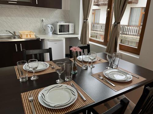 una mesa de comedor con platos y vasos. en St. Anastasia Apartments en Bansko