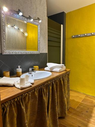 ein Bad mit einem Waschbecken und einem Spiegel in der Unterkunft Gite du Pavillon in Lens-Lestang