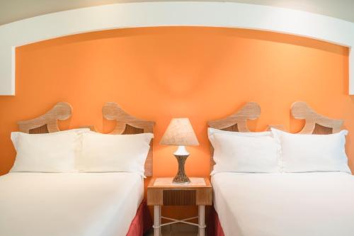 two beds in a room with an orange wall at Iberostar Waves Bahia - All Inclusive in Praia do Forte