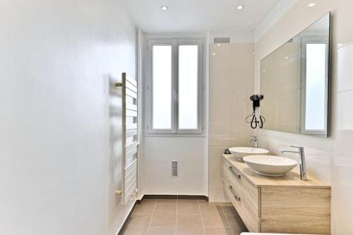ein Badezimmer mit zwei Waschbecken und zwei Spiegeln in der Unterkunft Appartement Luxueux Porte Maillot - Neuilly - III in Neuilly-sur-Seine