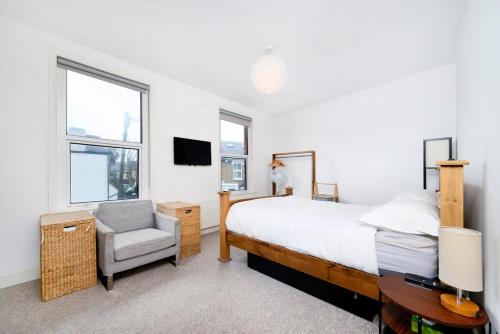 um quarto com uma cama, uma cadeira e uma janela em Charming 3BR Family-Friendly London Home em Londres