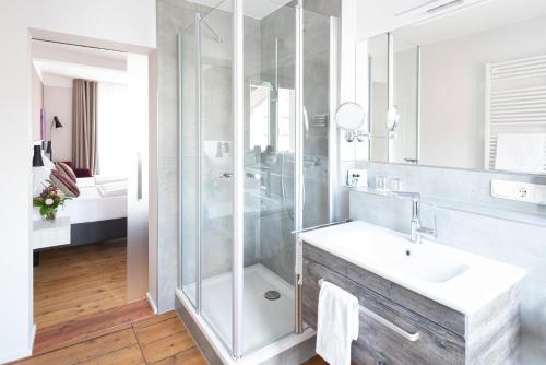 a bathroom with a glass shower and a sink at Adler Landhotel in Buergstadt